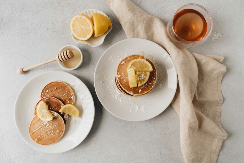 Pancakes mit Zitronenscheiben, Honig und Tee