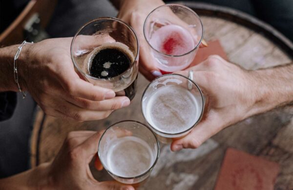 Vier Personen halten Gläser mit verschiedenen Biersorten in die Bildmitte
