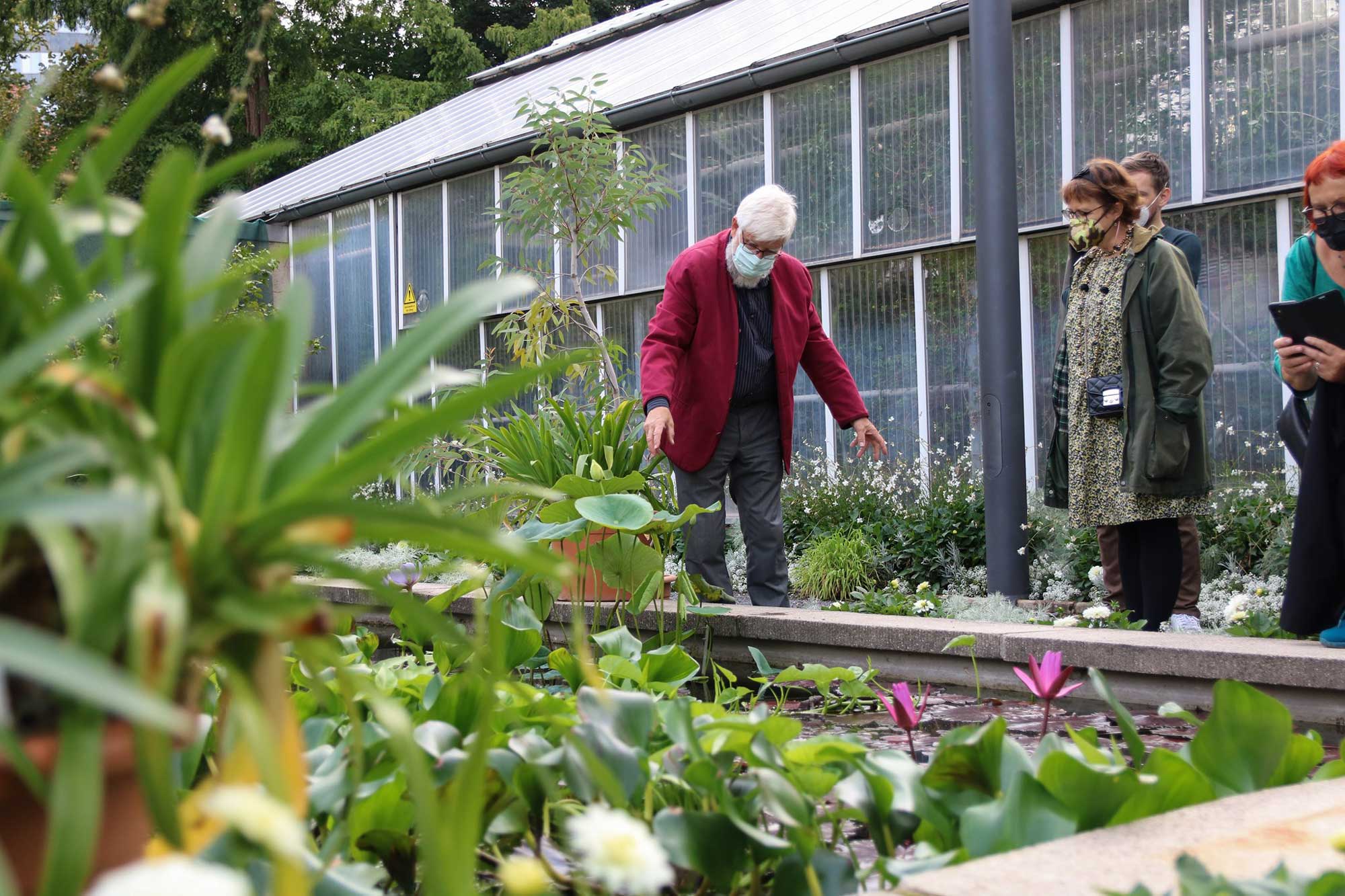 Ein Mann erklärt mehreren Personen etwas im Botanischen Garten Jena
